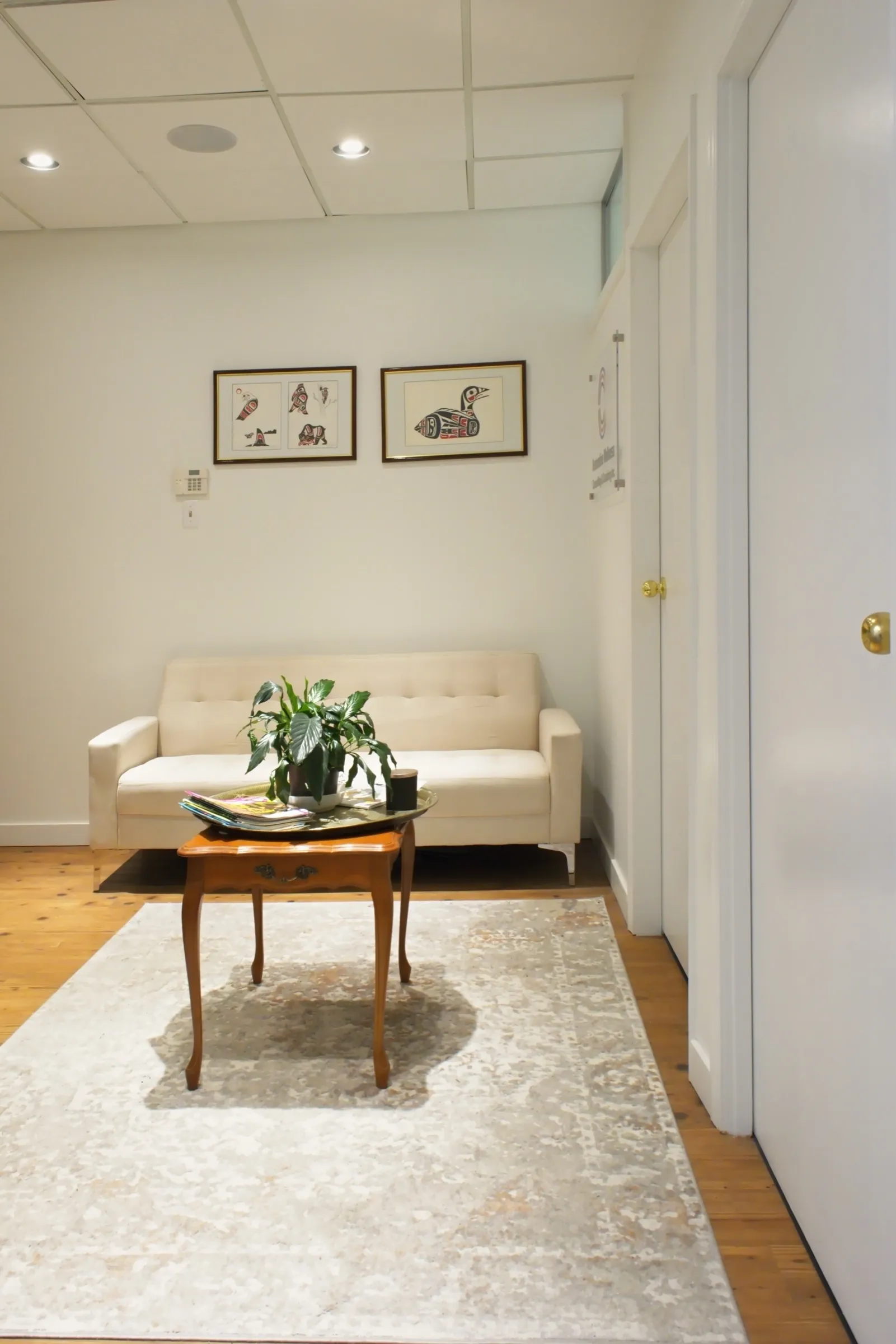 A quiet corner of the Martin Drive office: a cream sofa, a small wooden table and a plant.